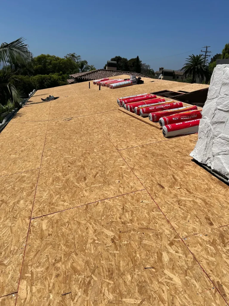 New roof decking with underlayment rolls staged for installation