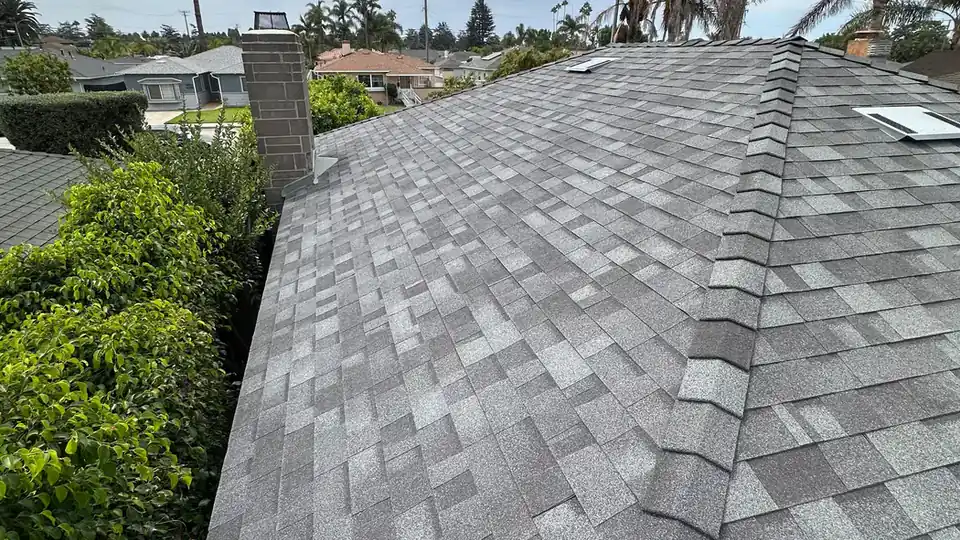 New asphalt shingle roof and ridge beside a brick chimney, installed by NEMA Roofing