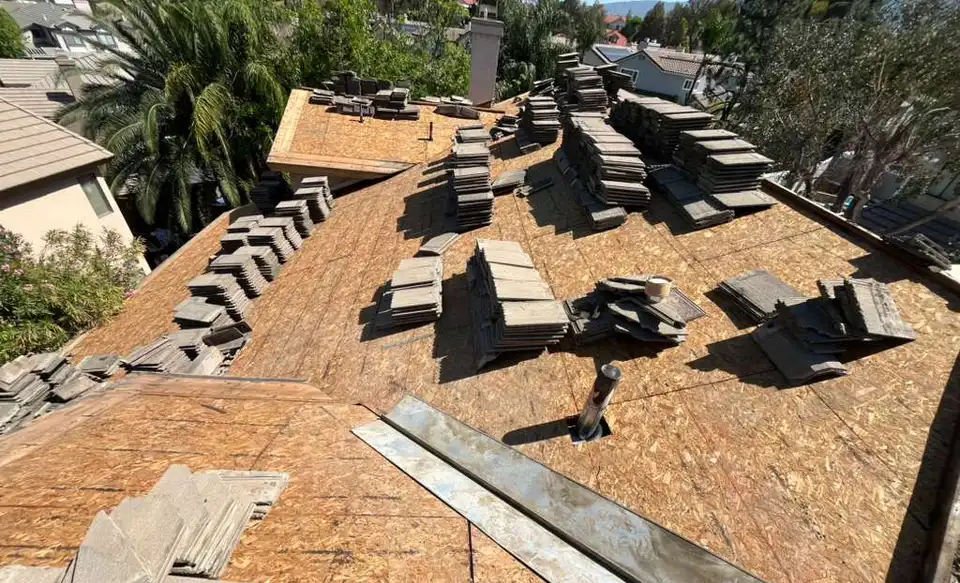 Concrete roof tiles lifted and stacked on a new wood deck during a tile roof re-deck in Corona