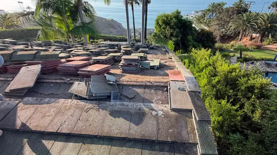 Tile roof tear-off on a coastal home with the ocean behind, by NEMA Roofing