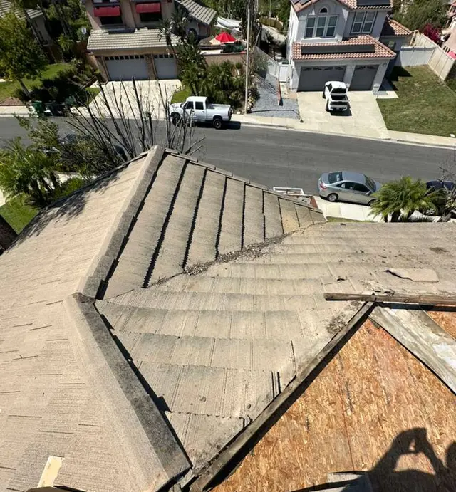 Concrete tile partly lifted with the roof deck exposed and a valley being rebuilt during a tile roof re-deck in Corona